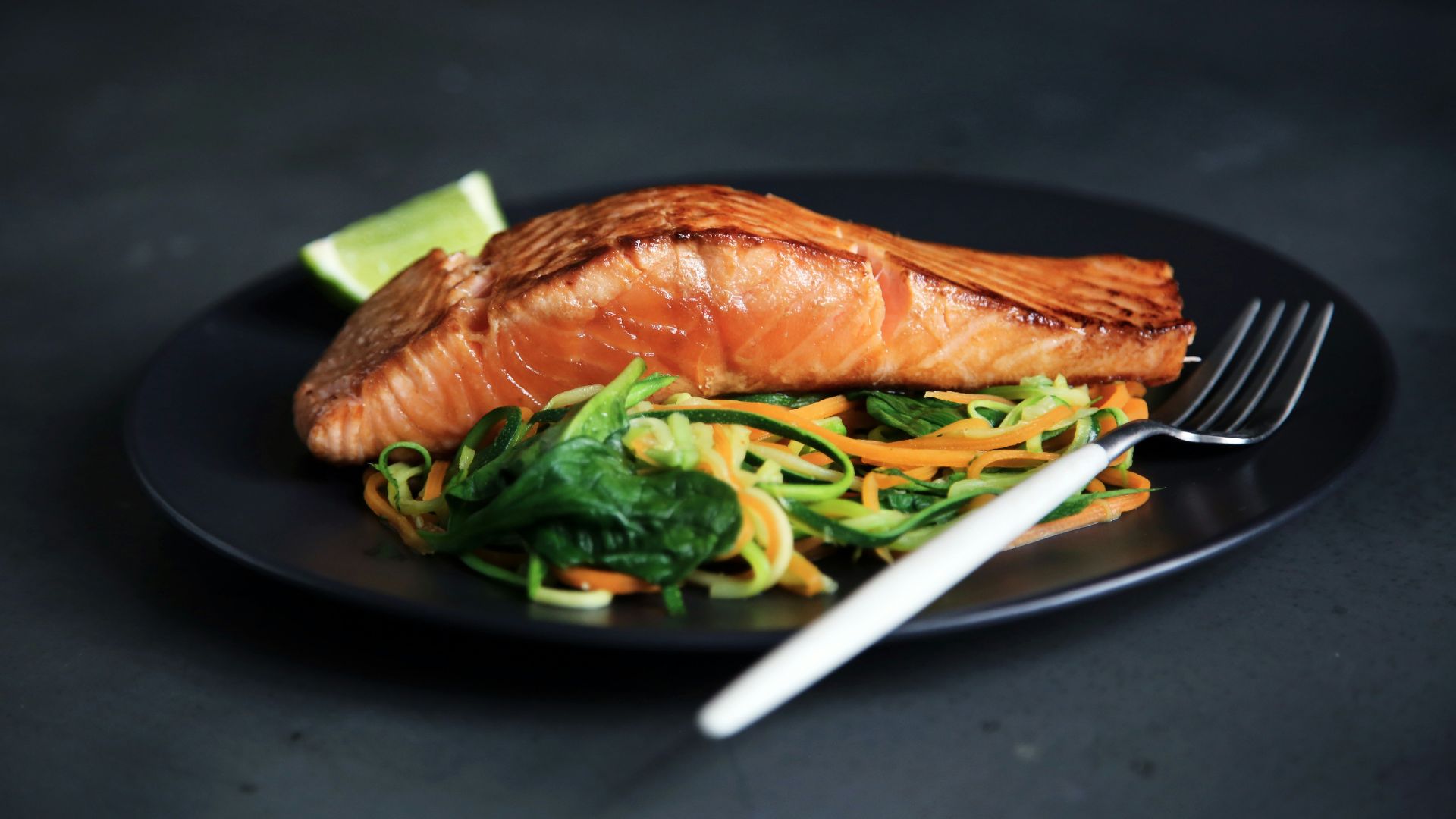 grilled fish, cooked vegetables, and fork on plate