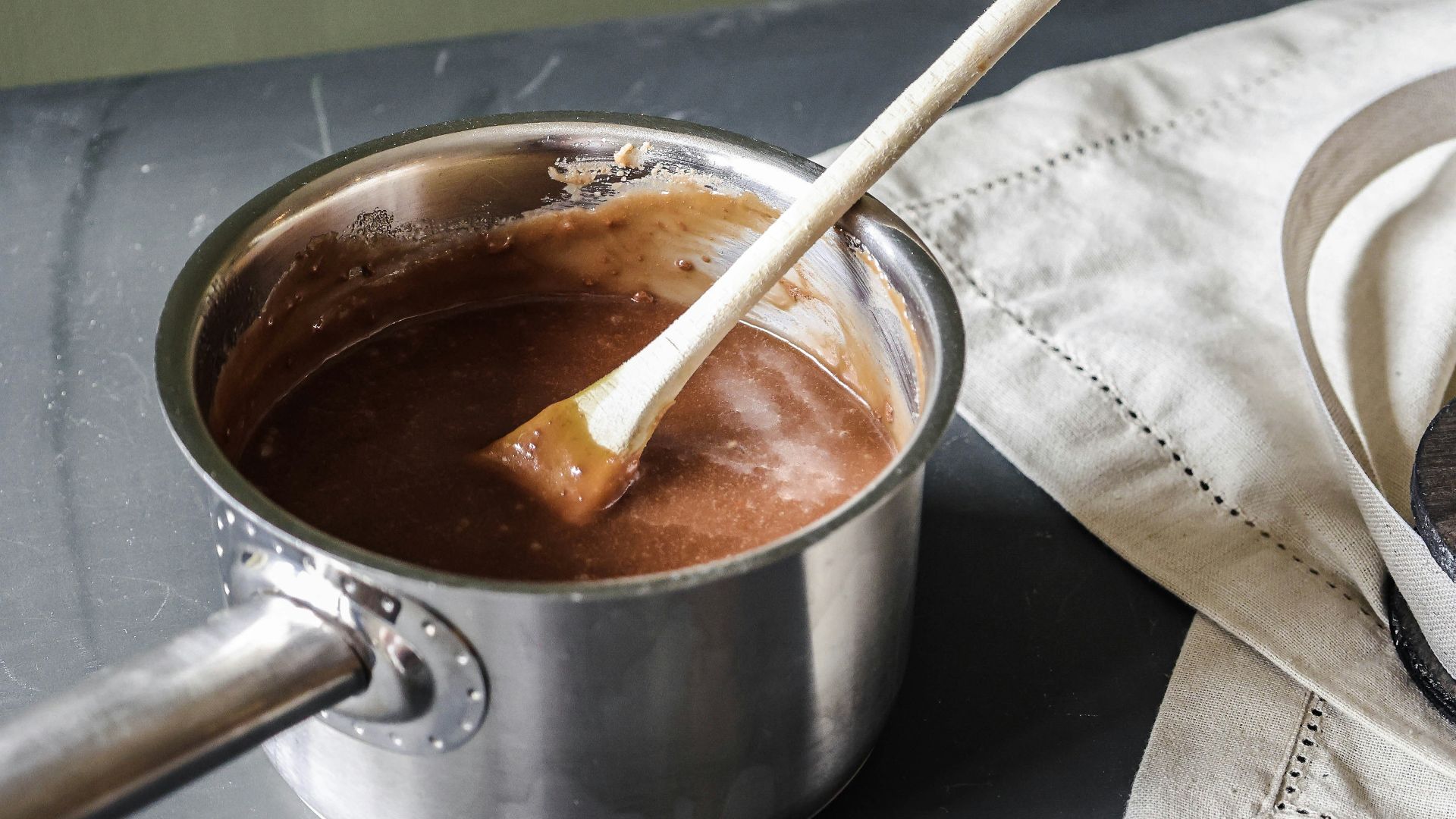 a pot of chocolate and a wooden spoon on a table