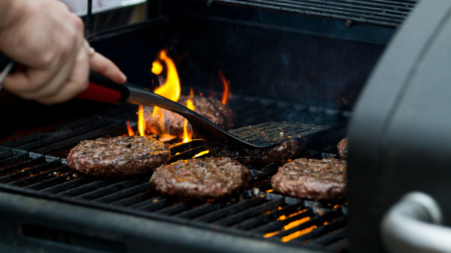 person grilling hamburger patties