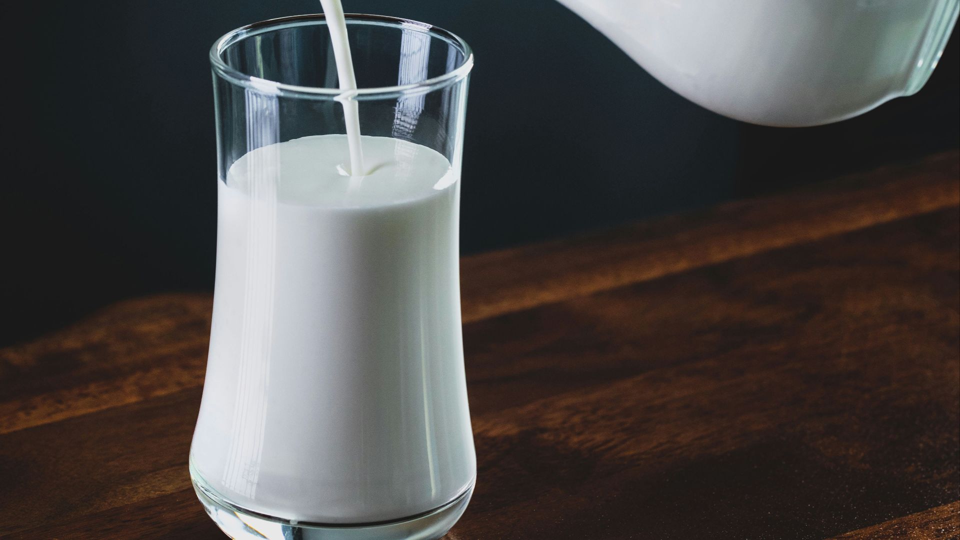 person pours milk into glass