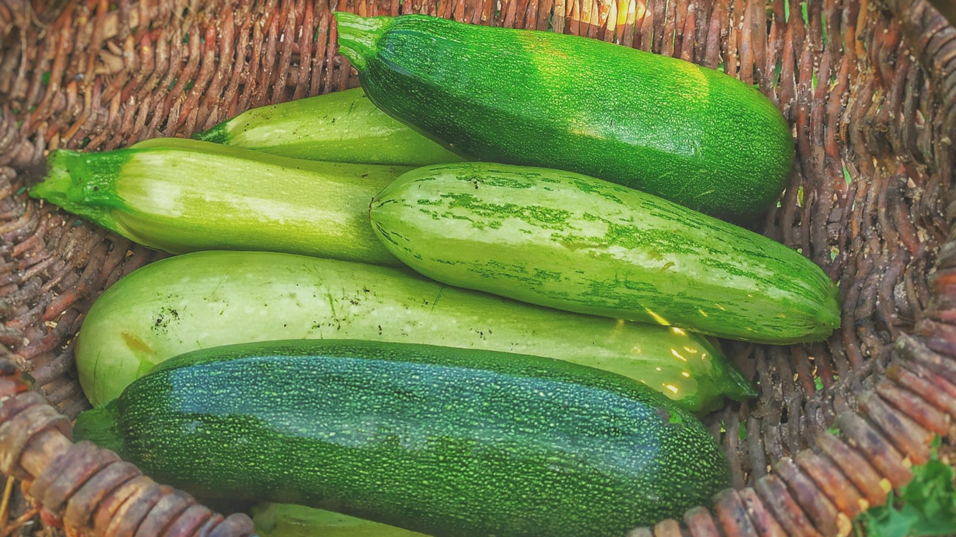 green cucumbers on round brown wicker basket
