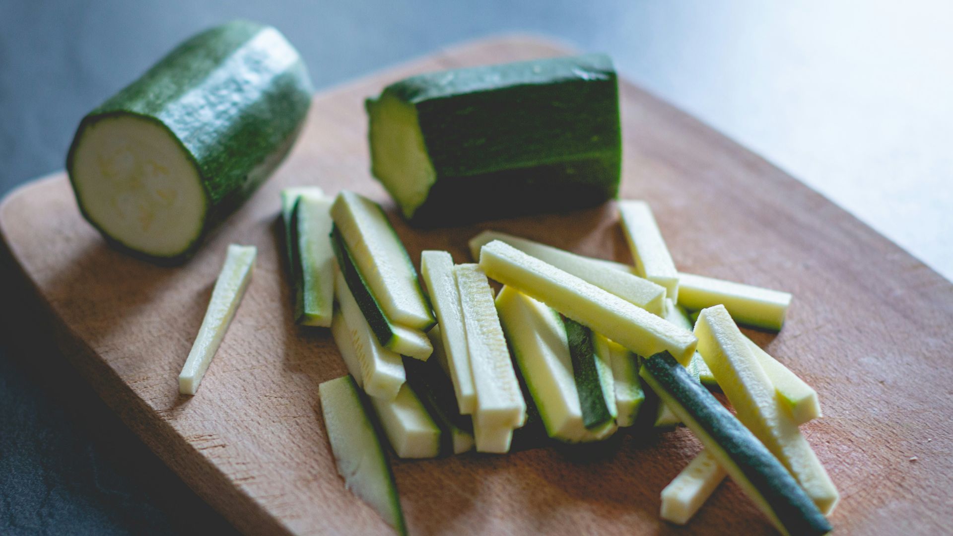 sliced green vegetable on brown wooden chopping board