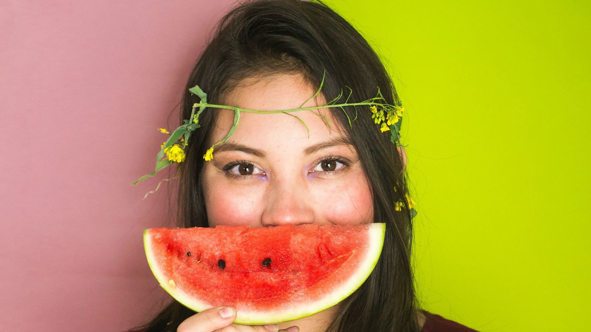 woman wearing maroon shirt holding sliced watermelon