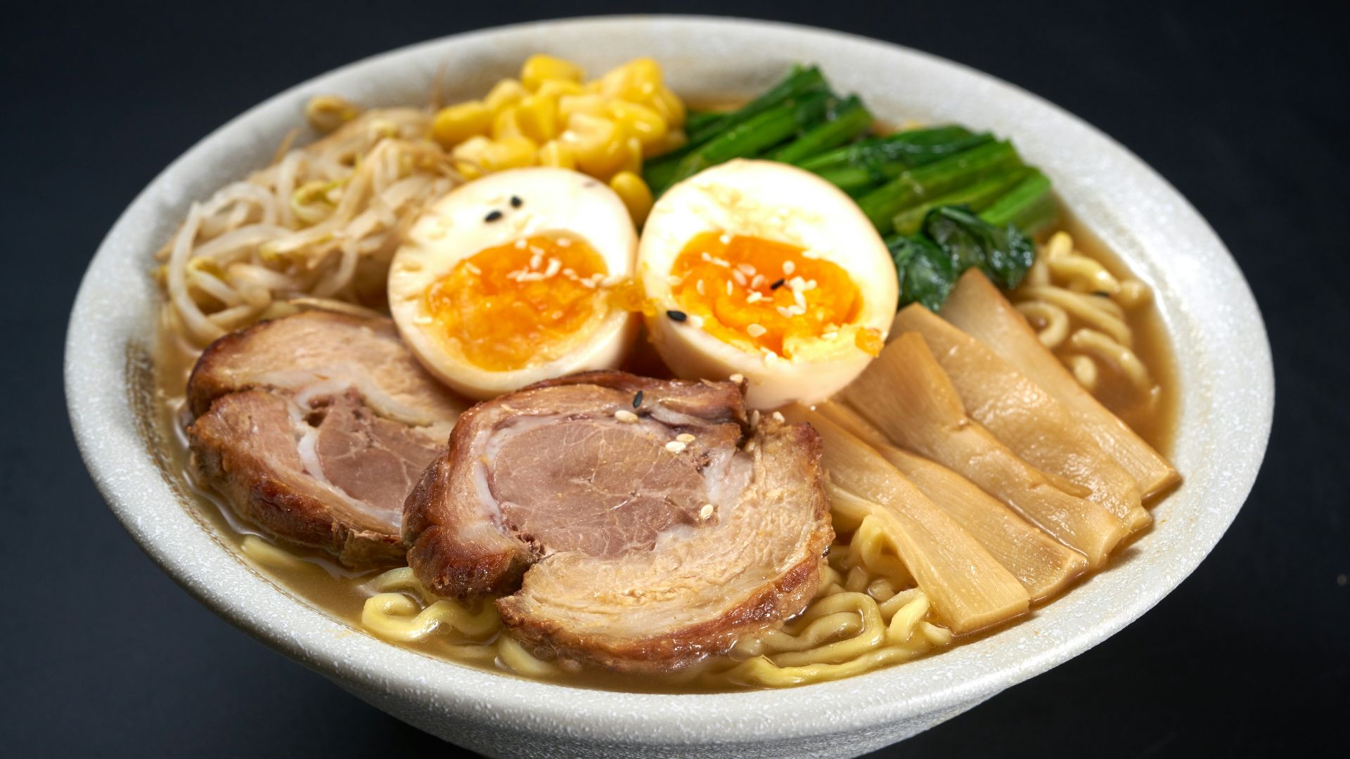 a bowl of ramen with meat, eggs, noodles and vegetables