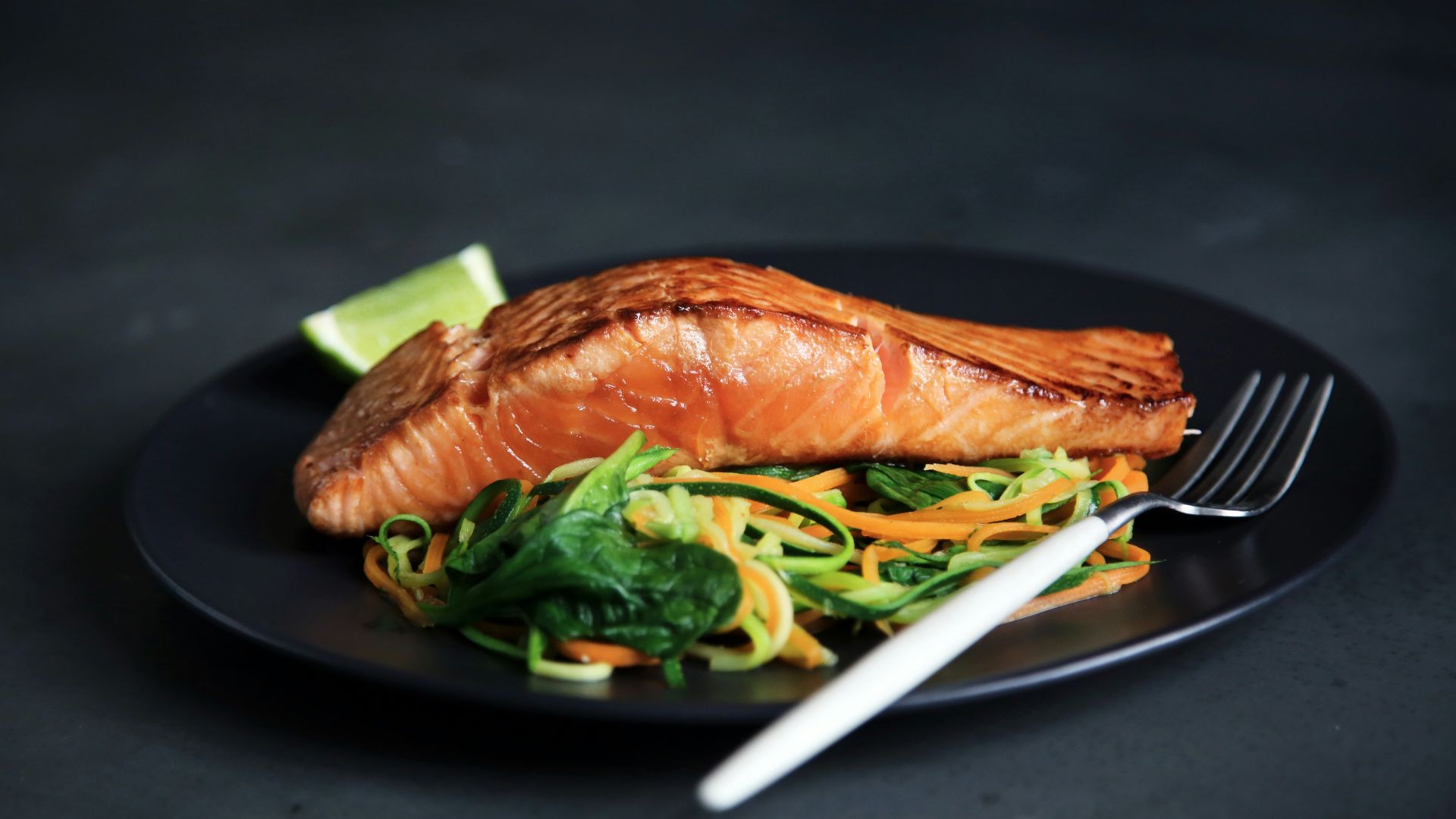 grilled fish, cooked vegetables, and fork on plate