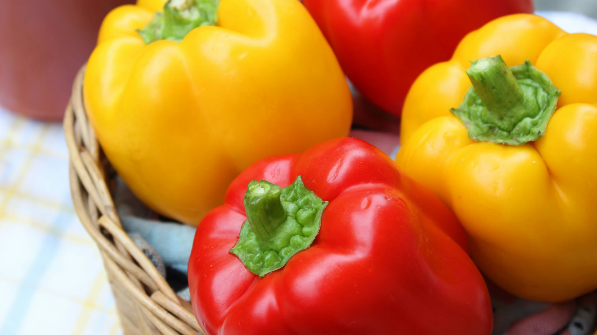 red and yellow bell peppers in brown woven basket