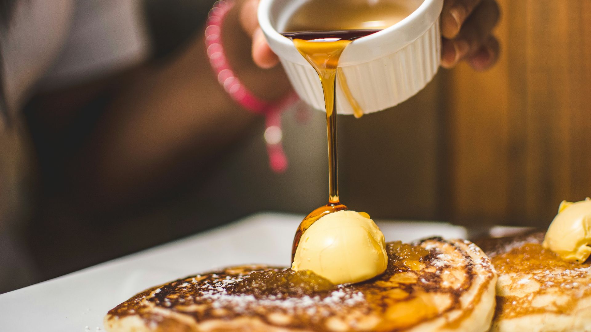 person pouring syrup into pancake