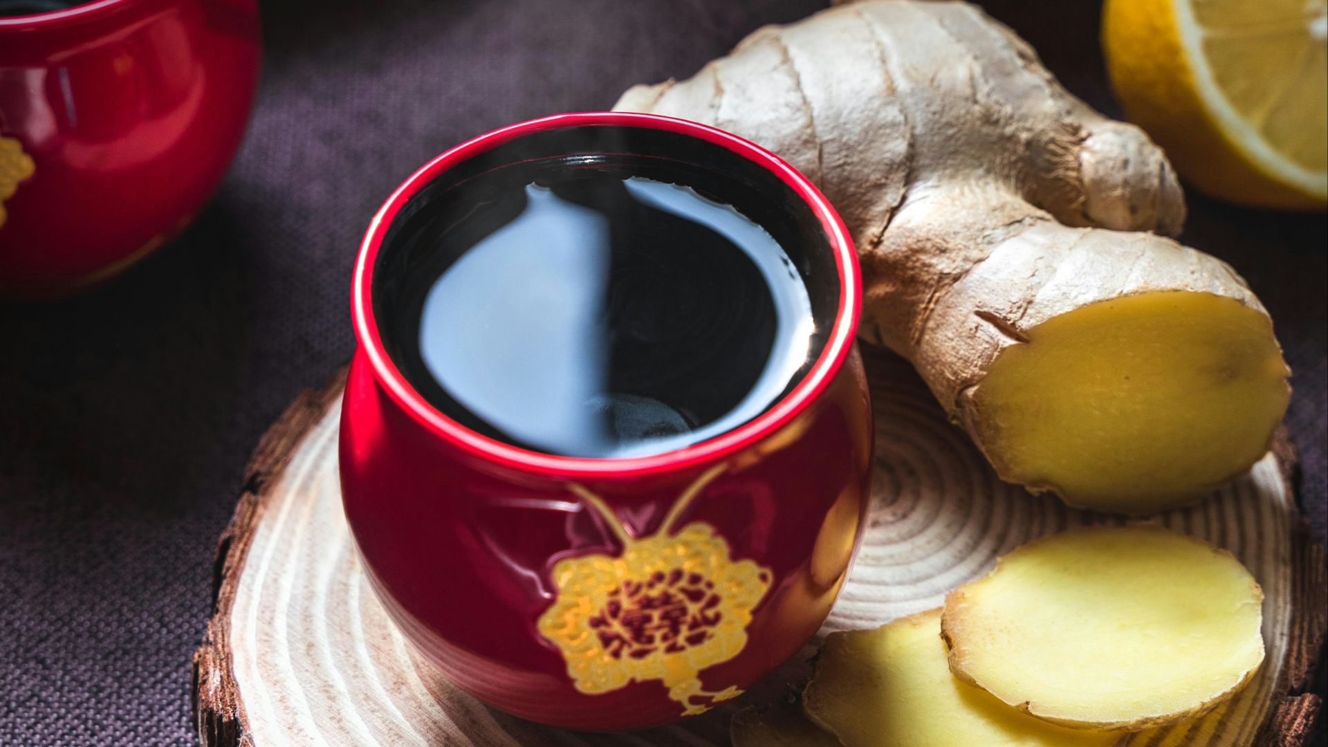 sliced lemon on red ceramic saucer beside red ceramic mug with black liquid