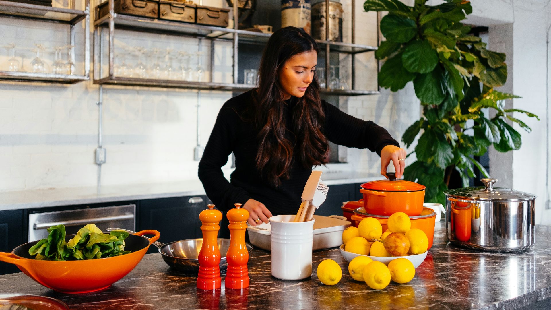 woman standing in front of fruits holding pot's lid