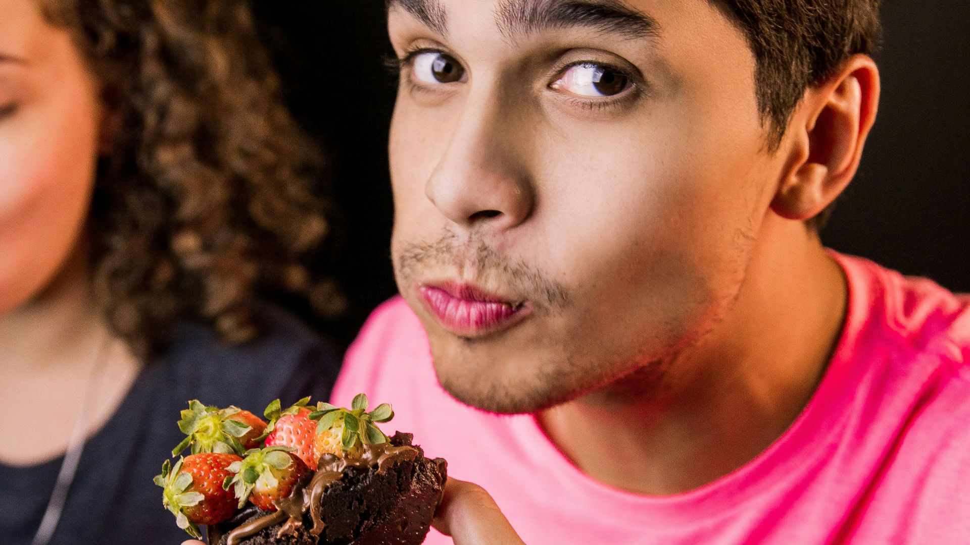 boy in pink crew neck t-shirt holding chocolate cake