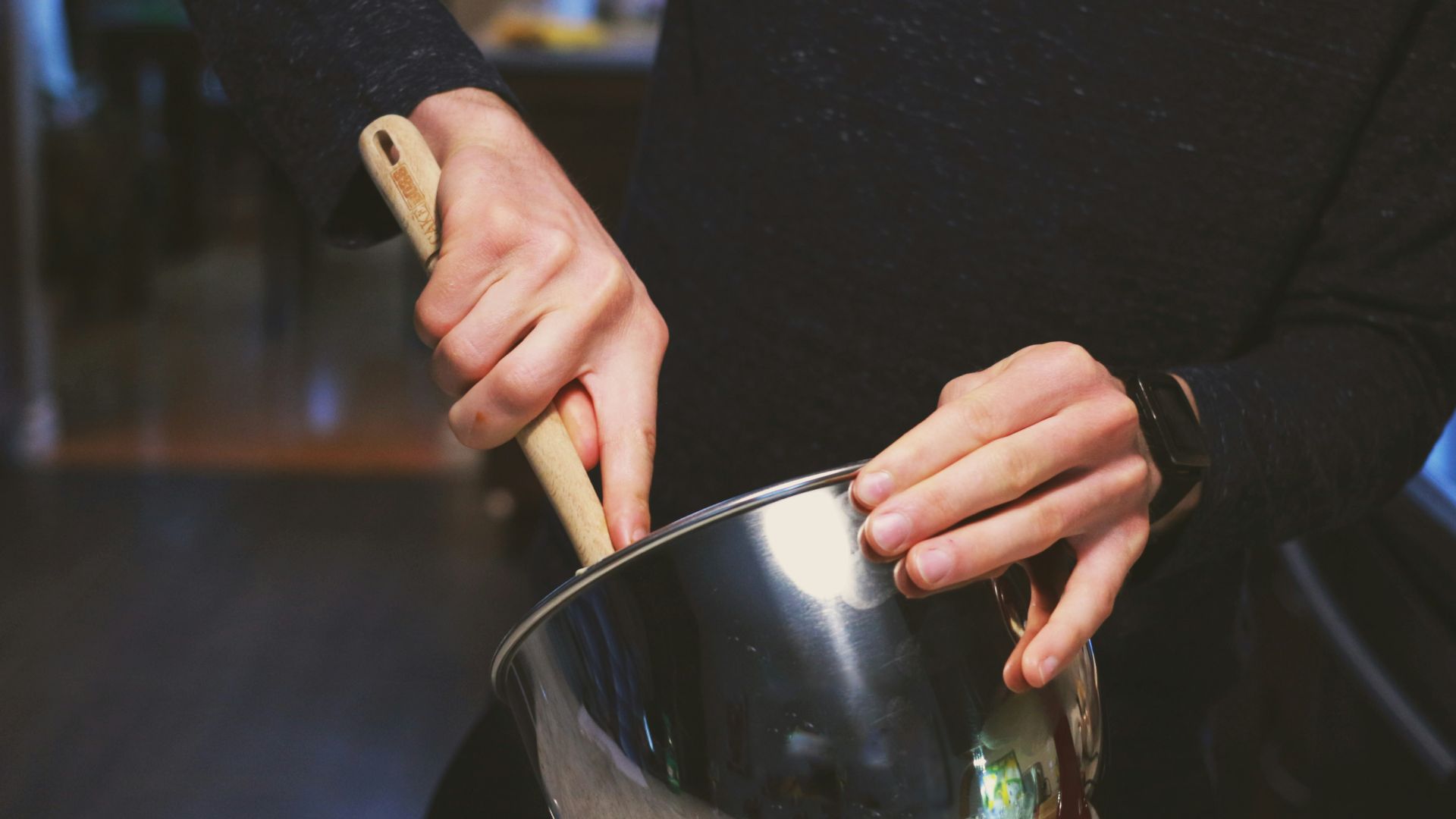 a person stirring a pot with a wooden spoon