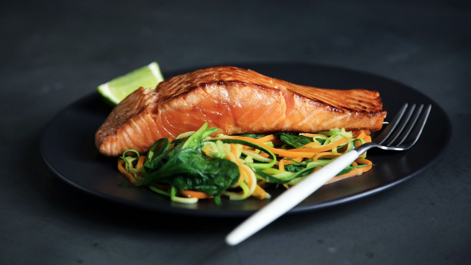 grilled fish, cooked vegetables, and fork on plate