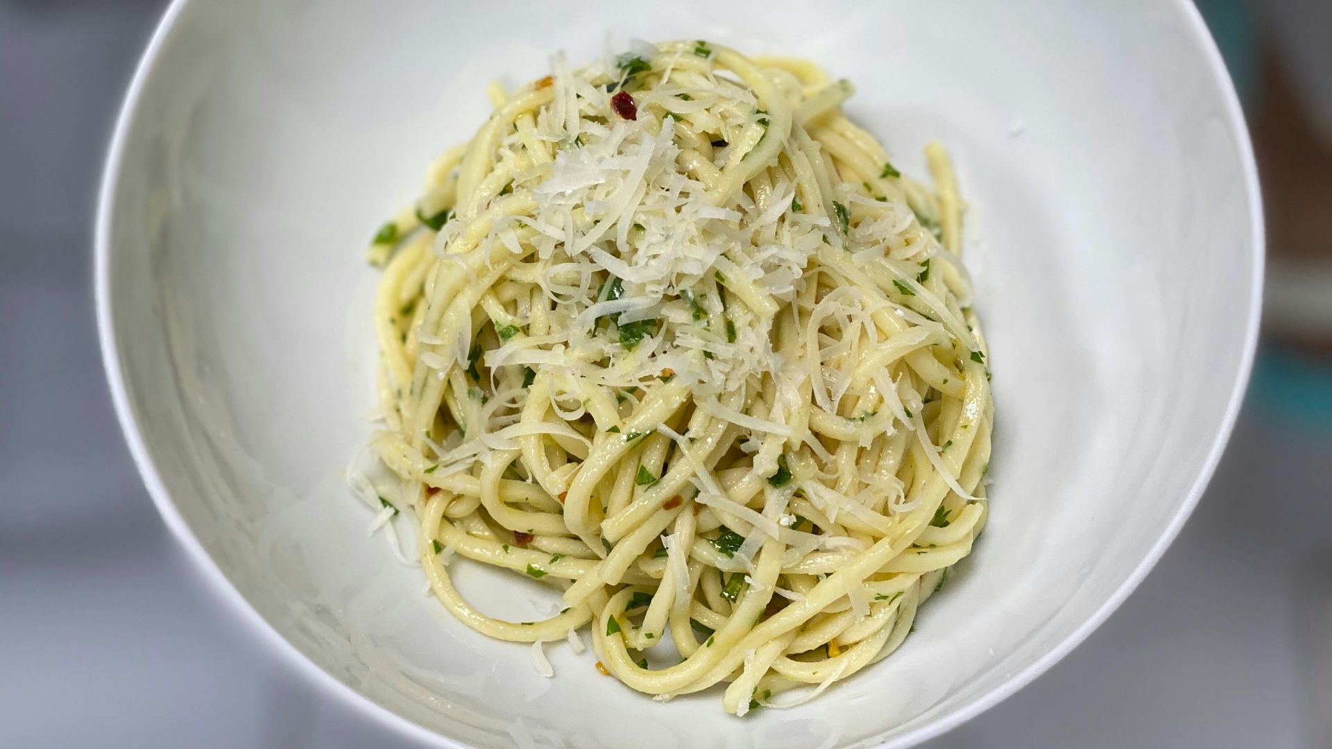 A person holding a bowl of spaghetti in their hand