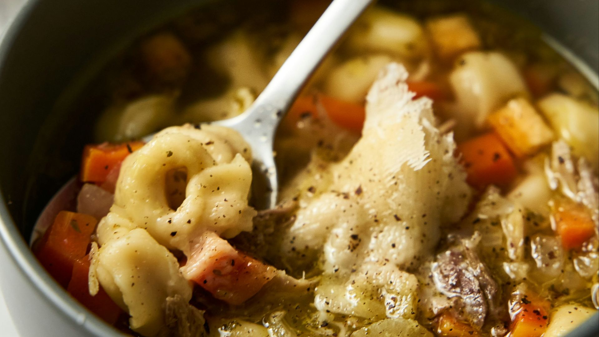 a bowl of pasta soup with a spoon in it