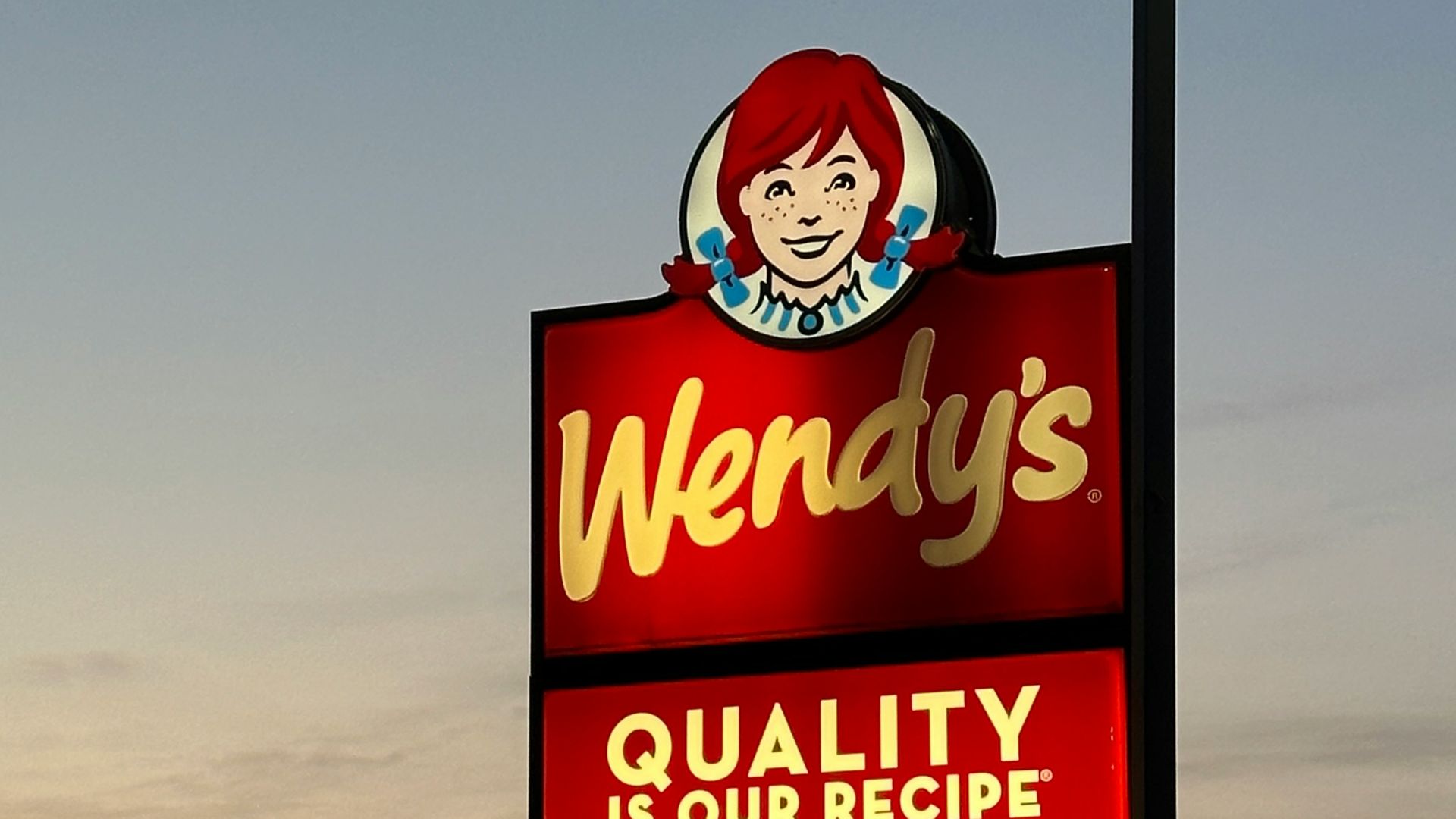 a sign for wendy's restaurant in a parking lot
