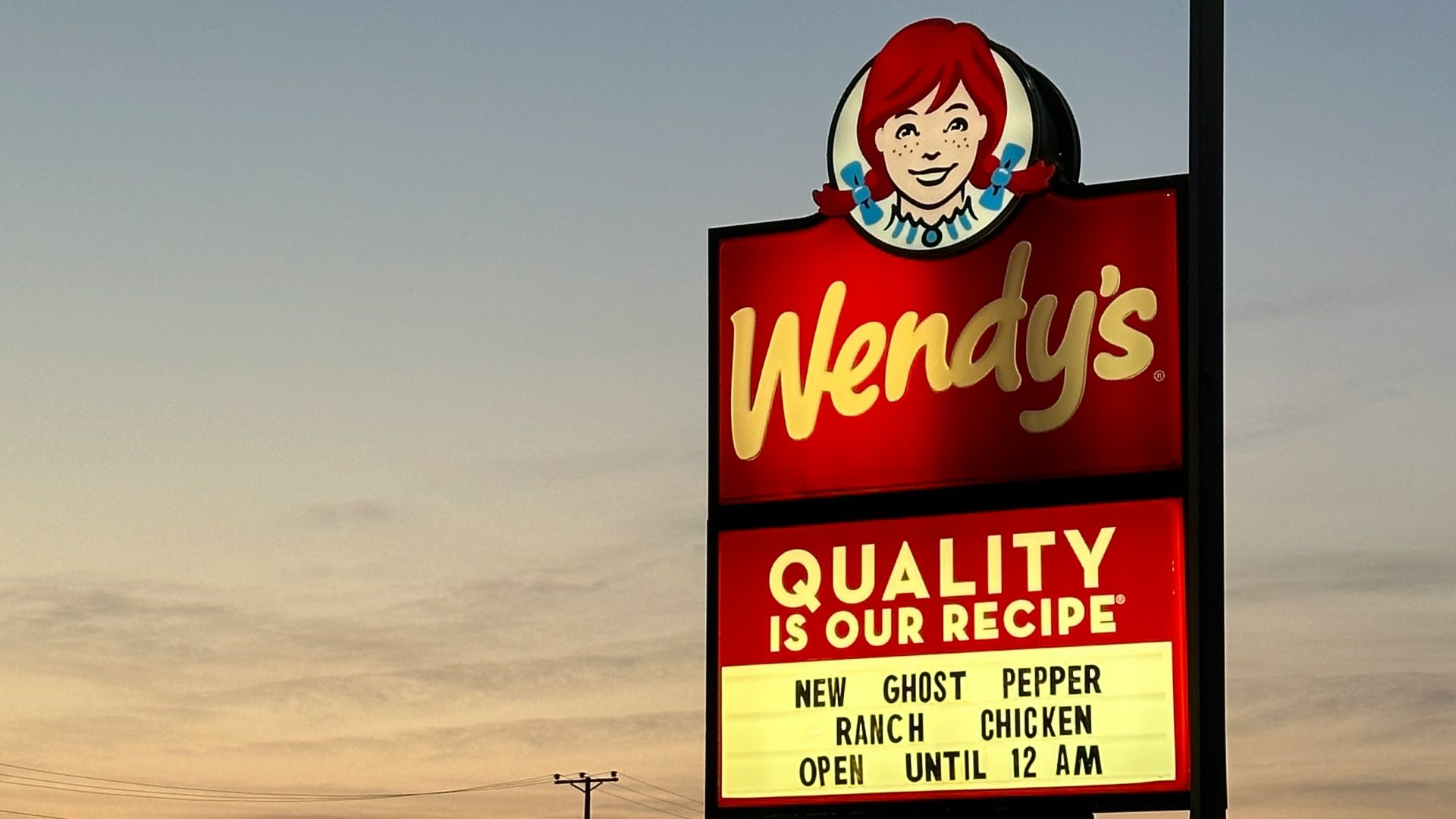 a sign for wendy's restaurant in a parking lot