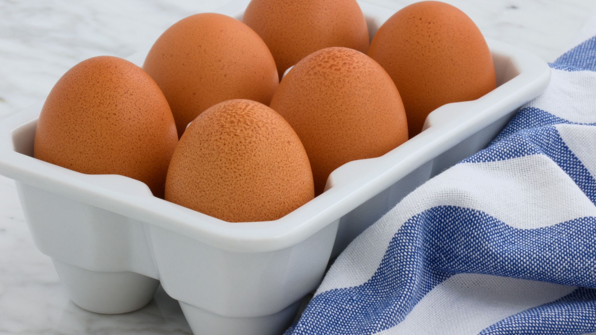six brown eggs in white tray