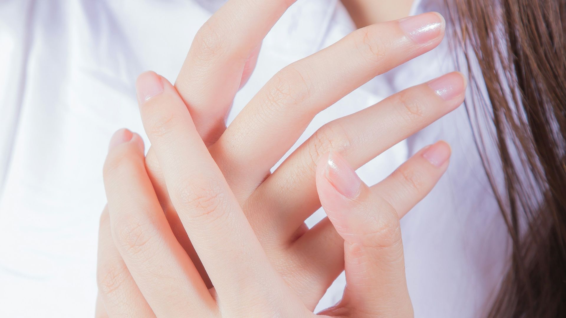 woman in white shirt covering her face with her hand