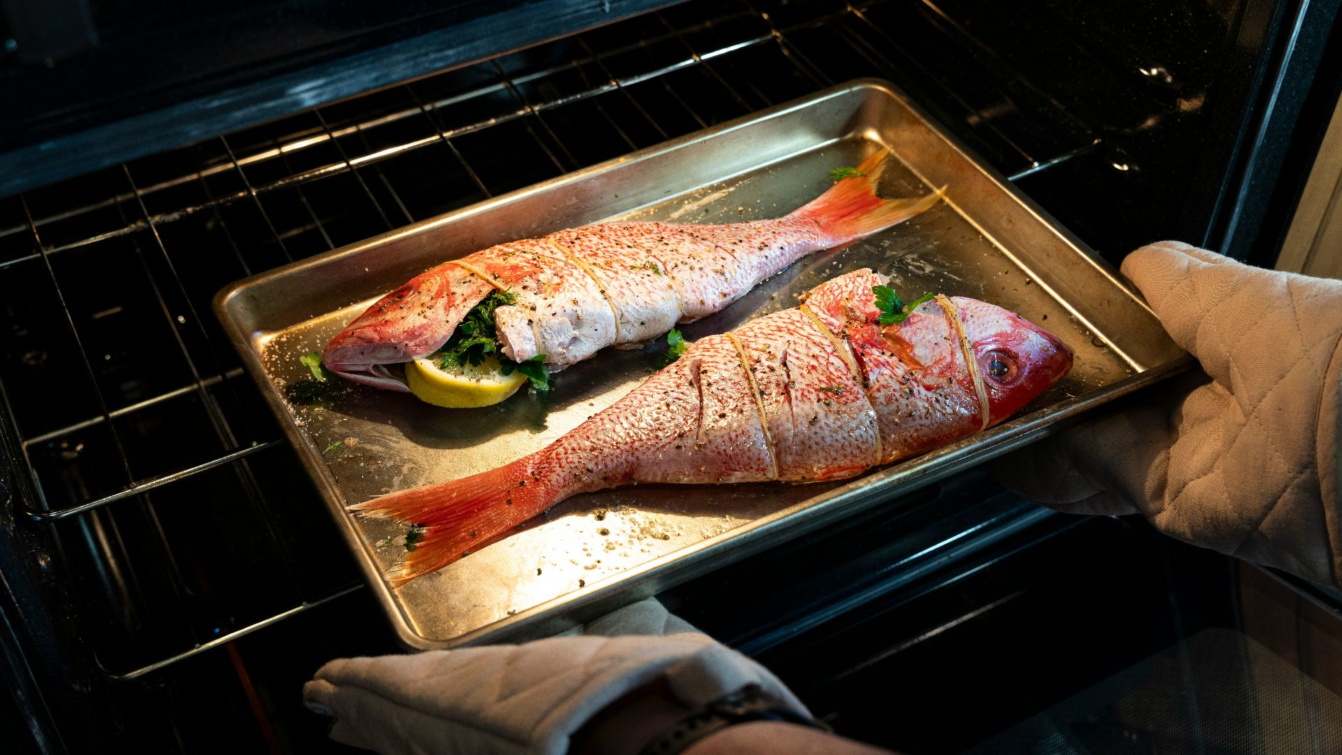 a person pulling a fish out of an oven