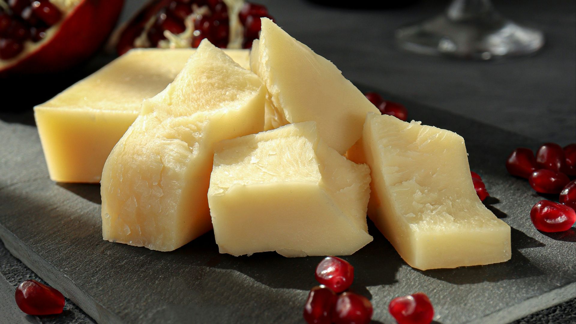 sliced cheese on black plate beside wine glass