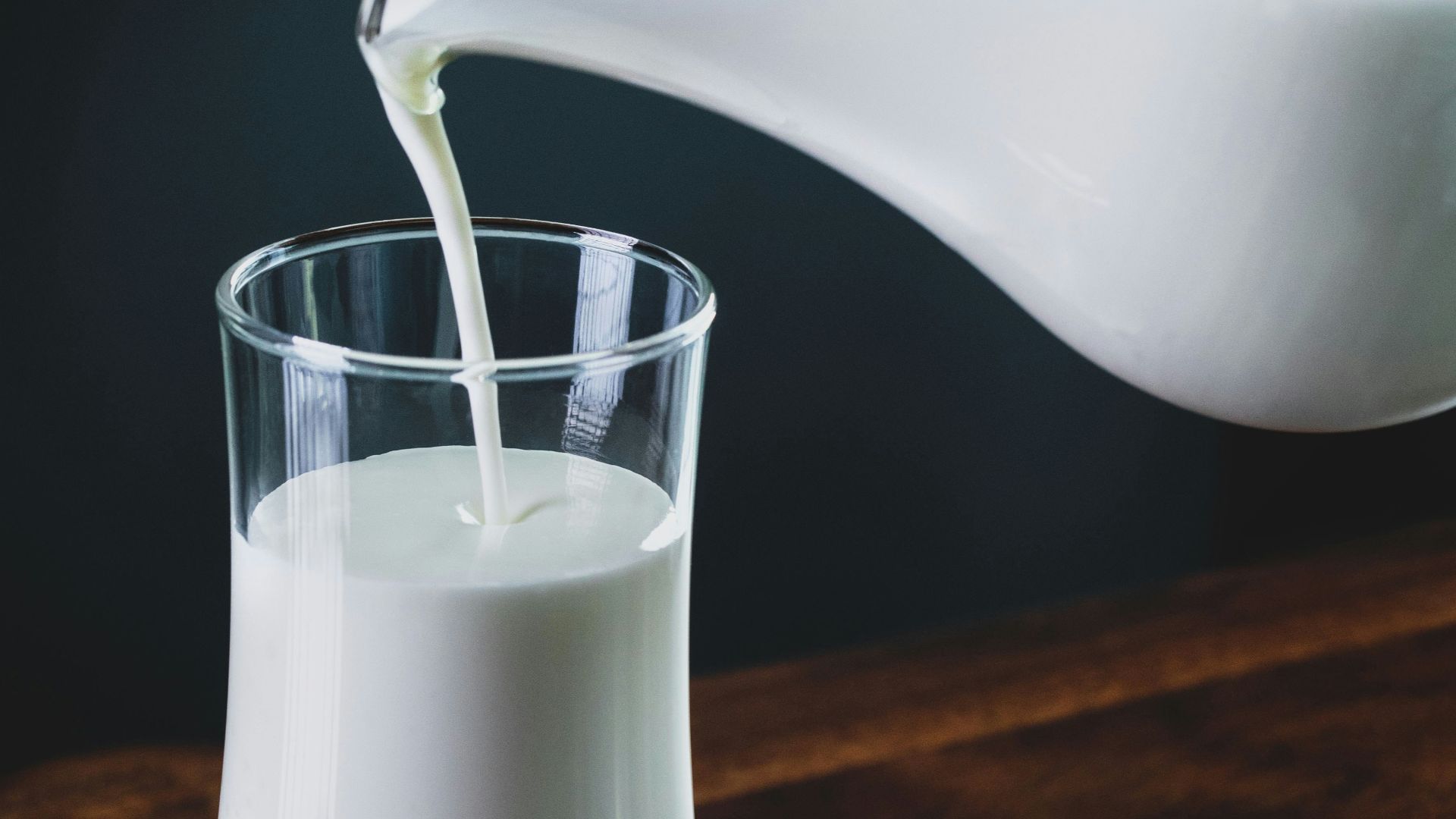 person pours milk into glass
