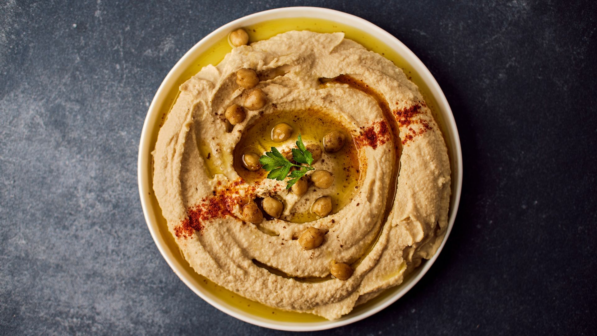 a bowl of hummus with a garnish on top