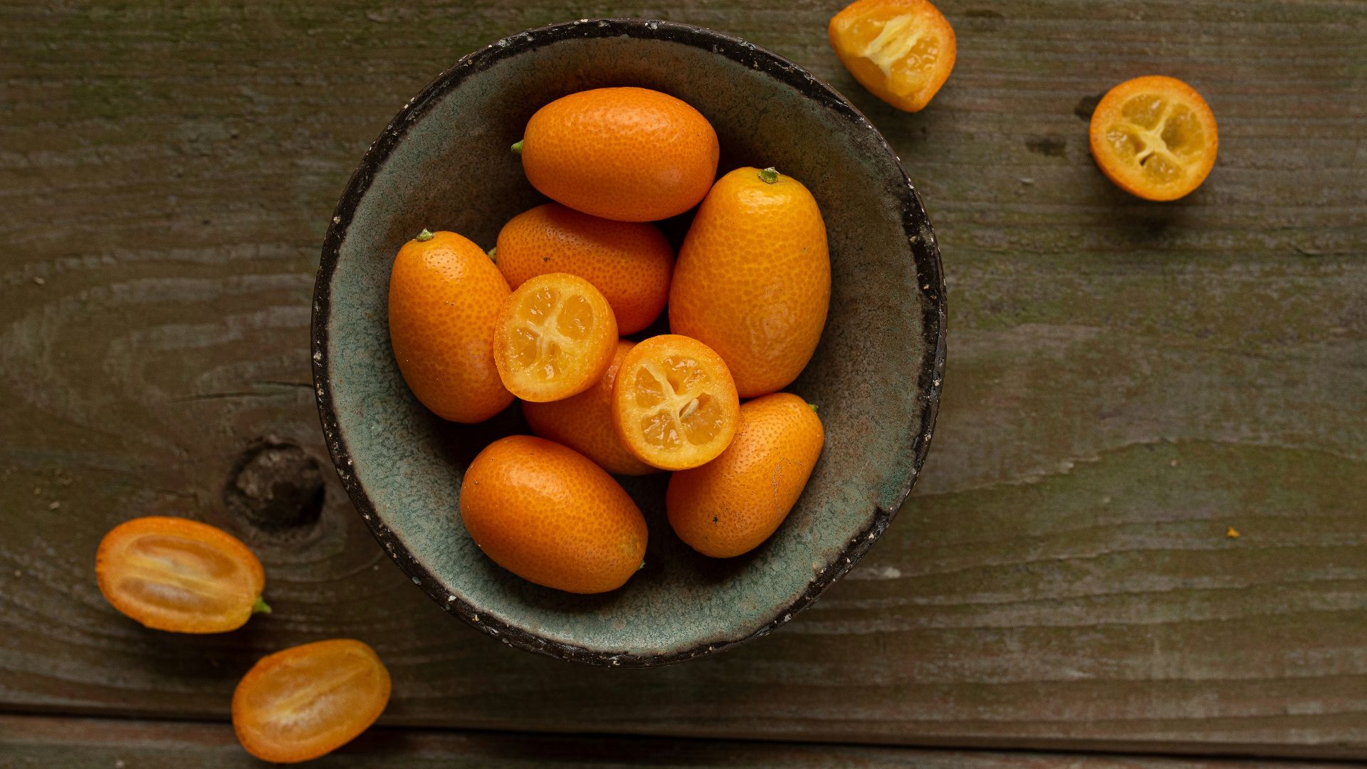 a bowl filled with oranges on top of a wooden table