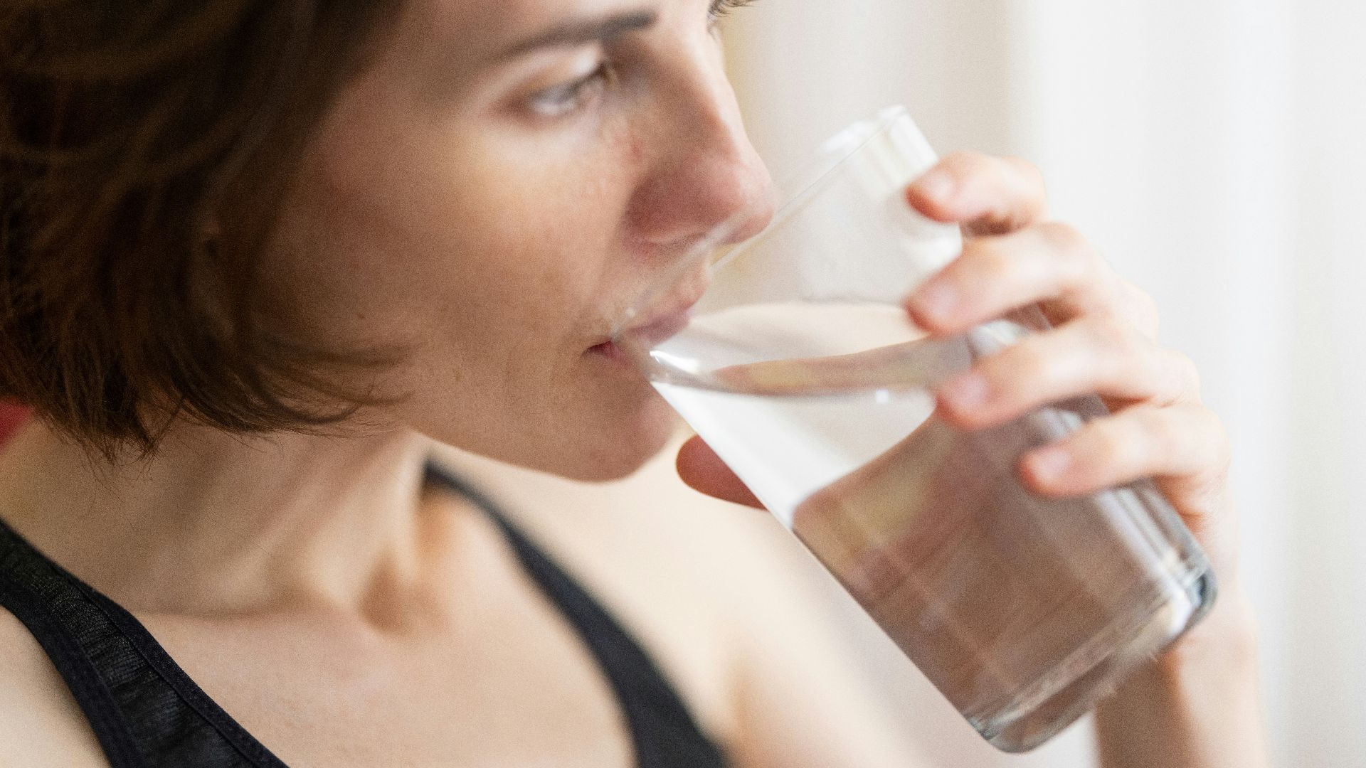woman in black tank top drinking water