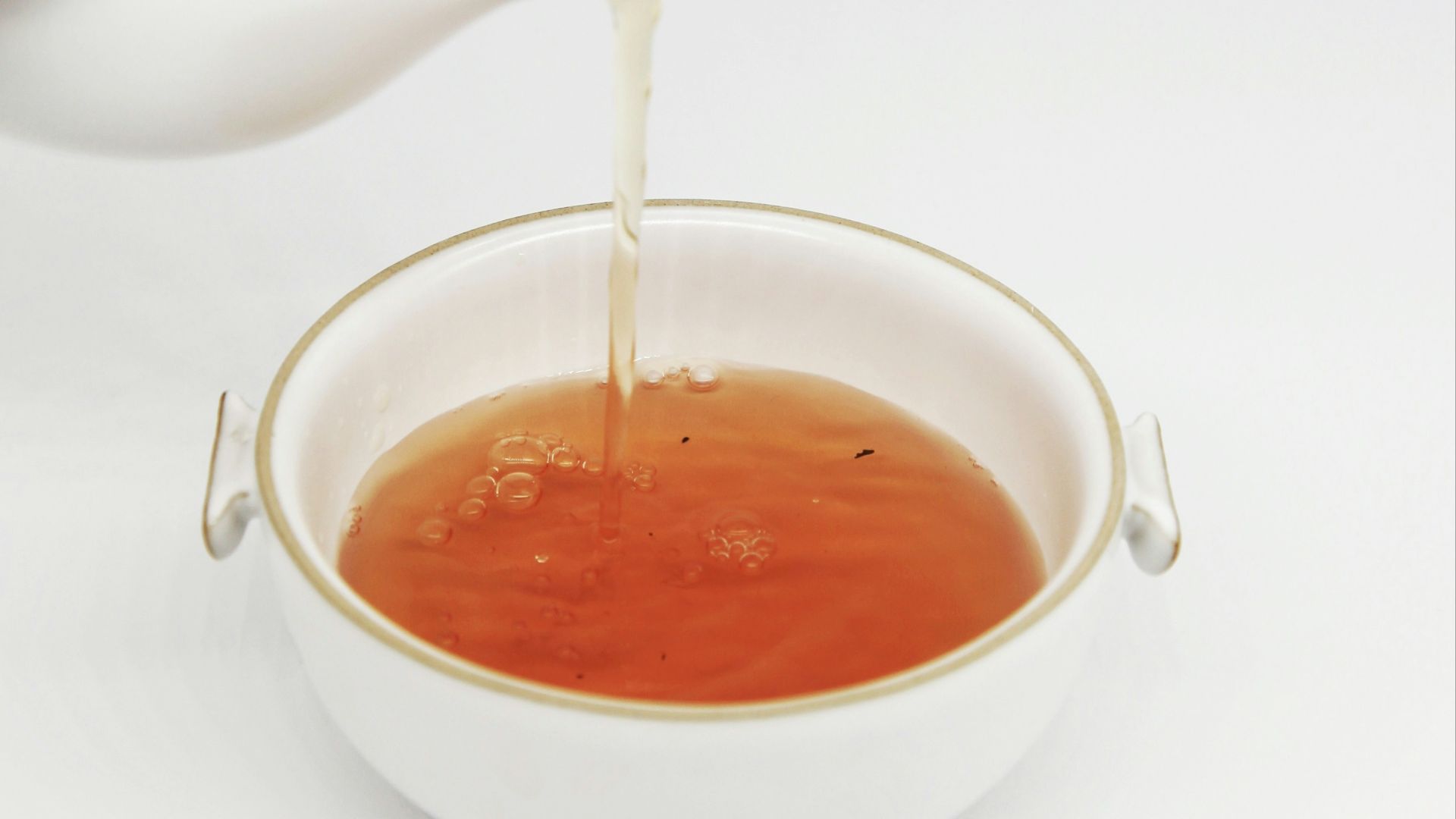 tea pours into white teacup