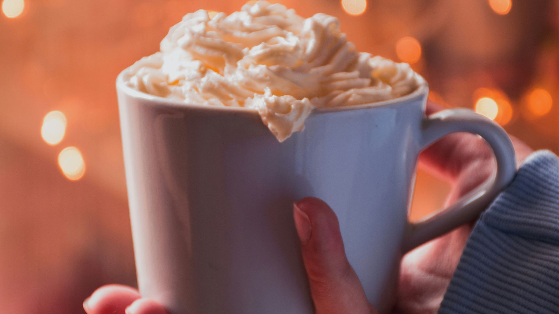person holding white ceramic mug with white cream