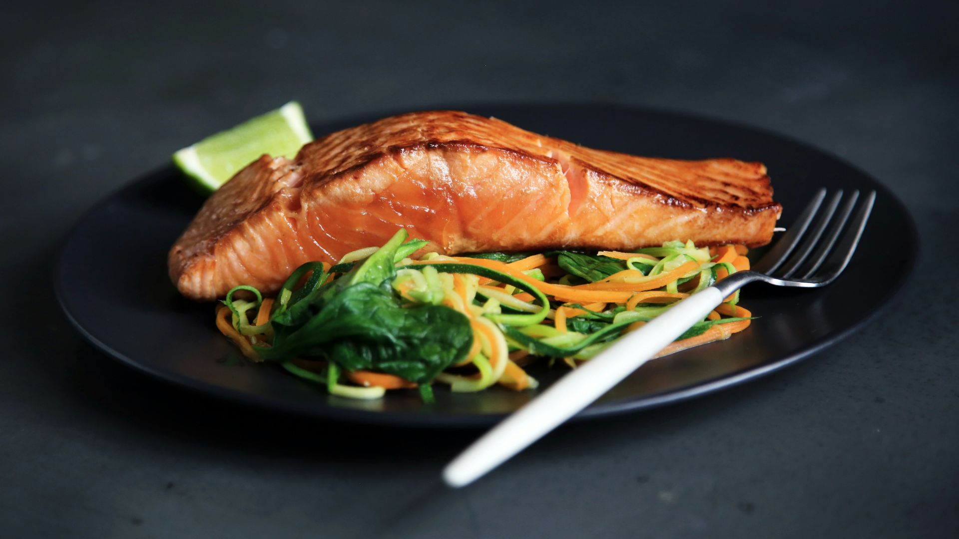 grilled fish, cooked vegetables, and fork on plate