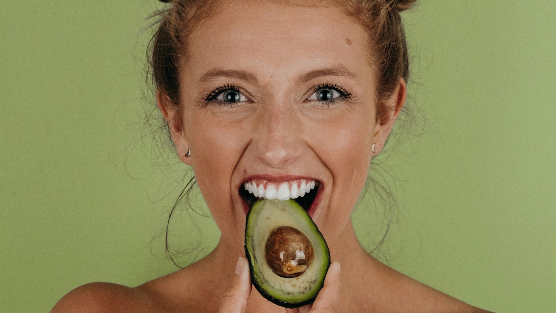 woman holding sliced avocado