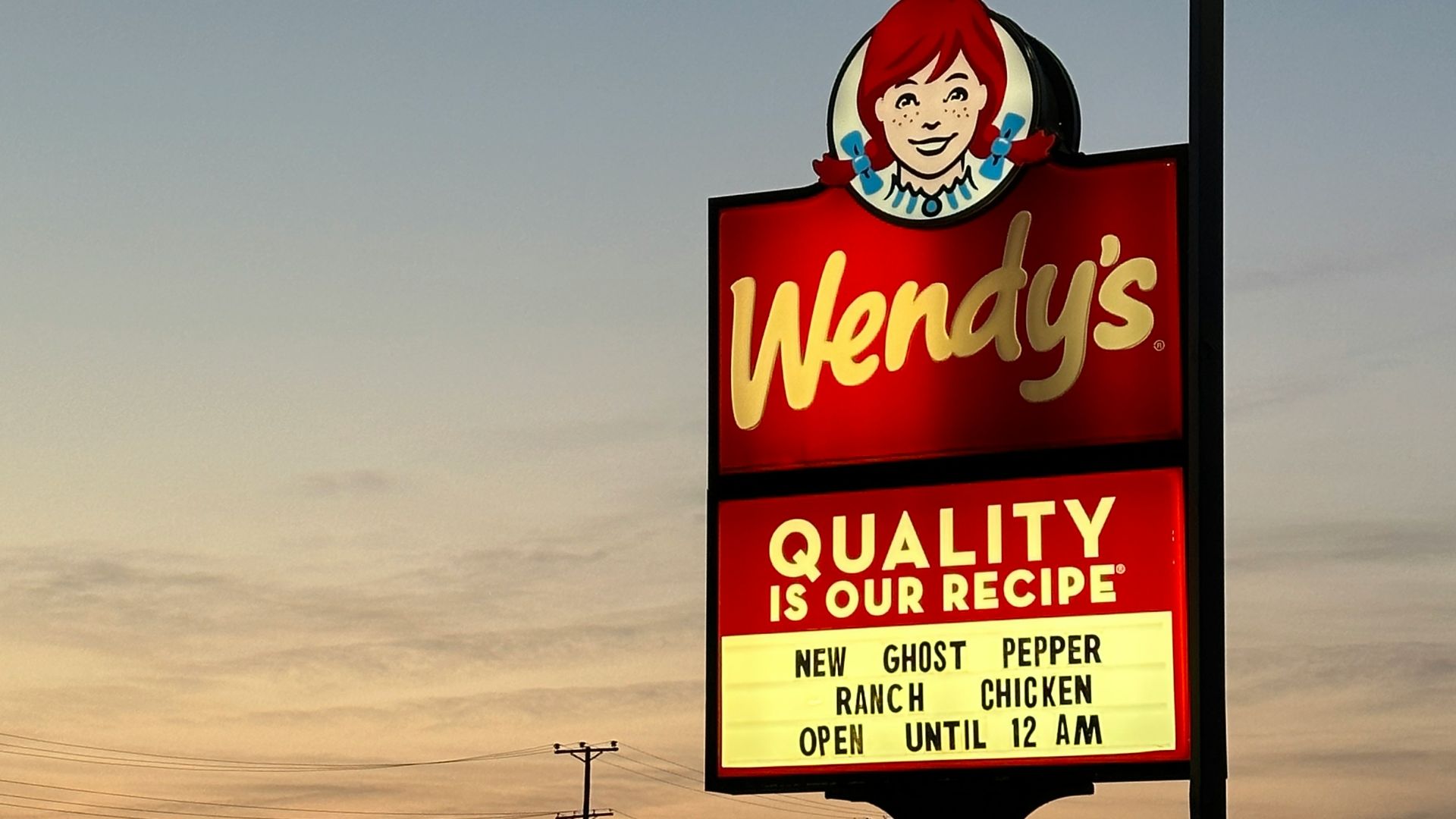 a sign for wendy's restaurant in a parking lot