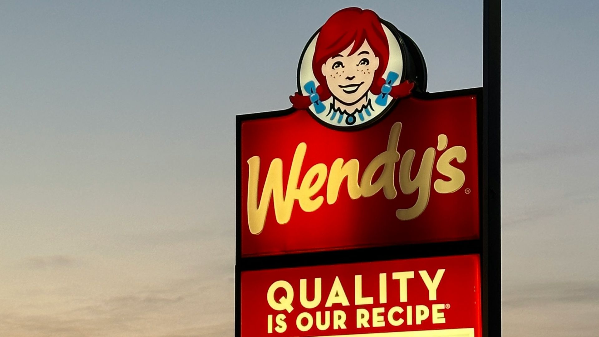 a sign for wendy's restaurant in a parking lot
