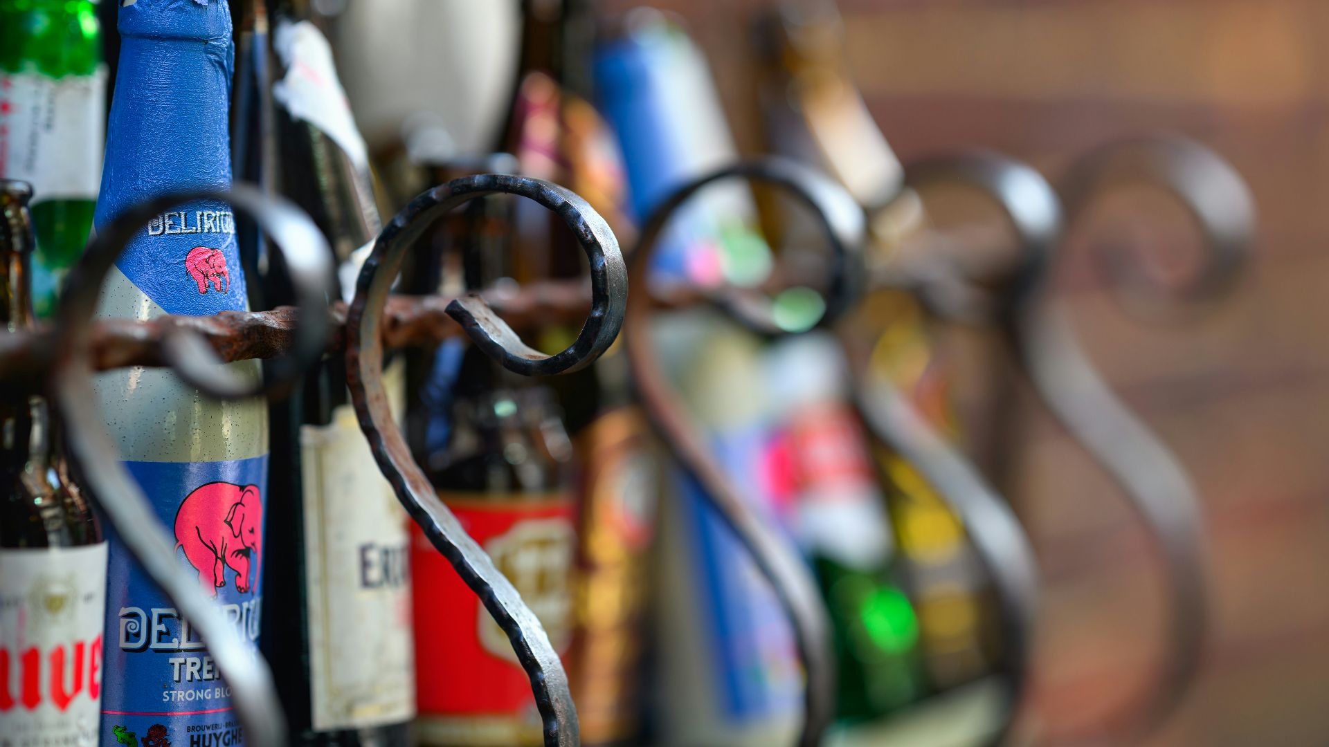 A bunch of beer bottles hanging from a metal rack