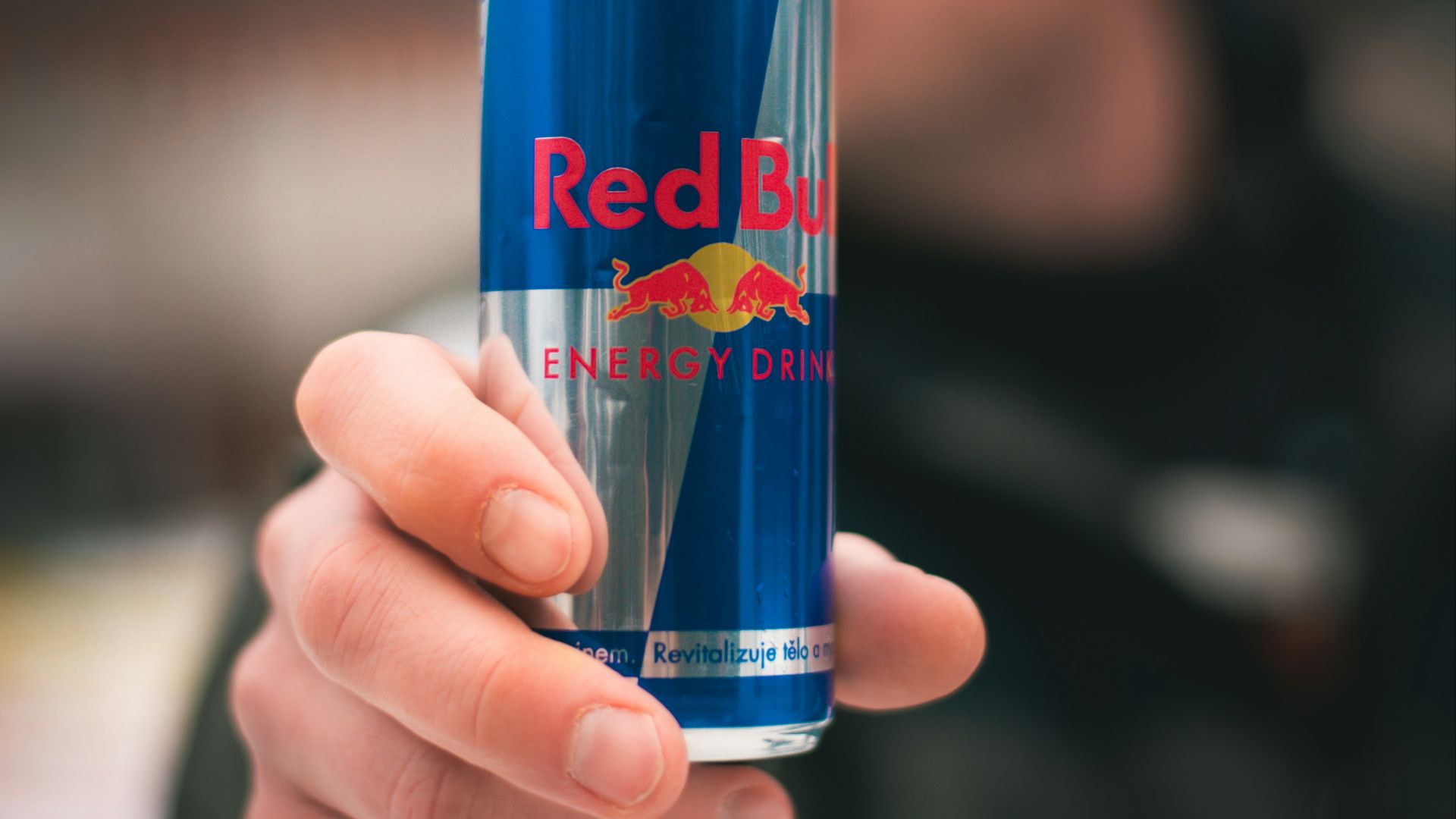 person holding red bull energy drink can