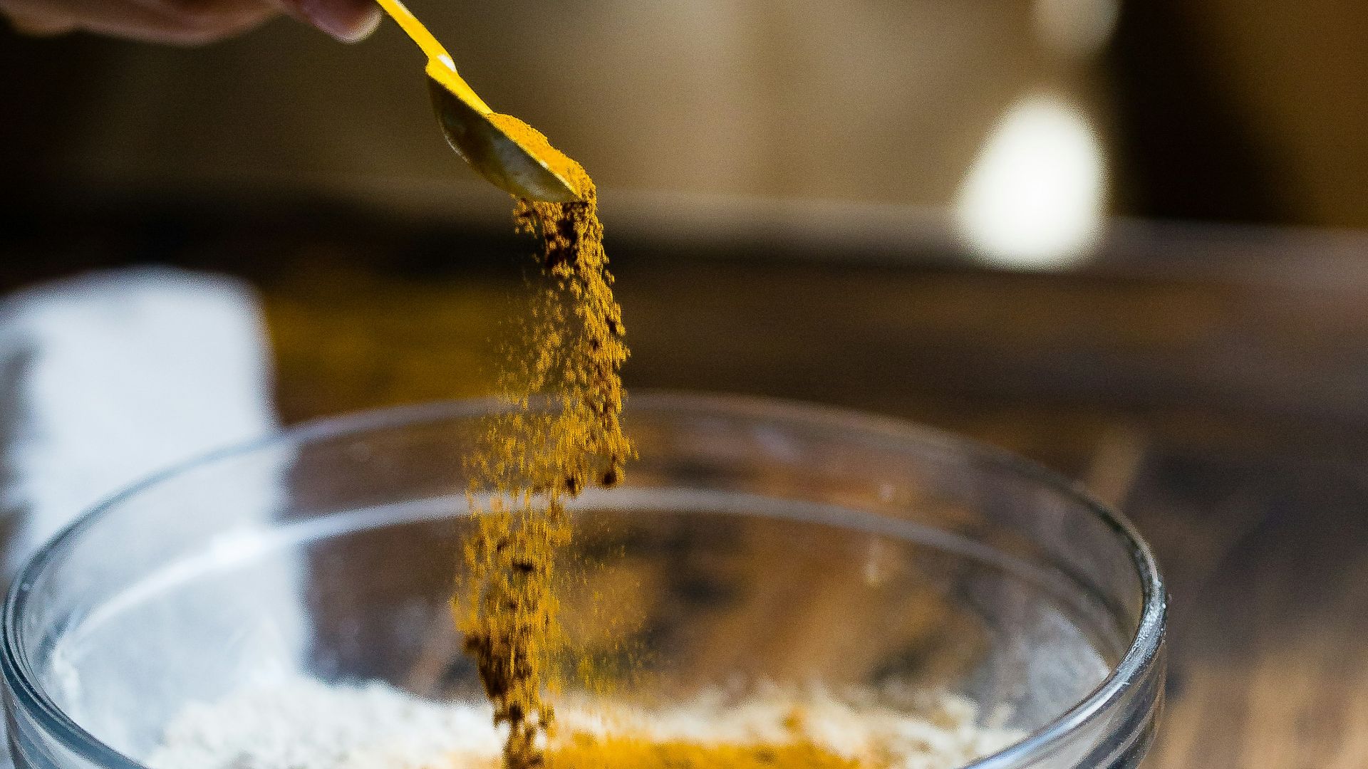 person pouring seasonings on clear glass bowl