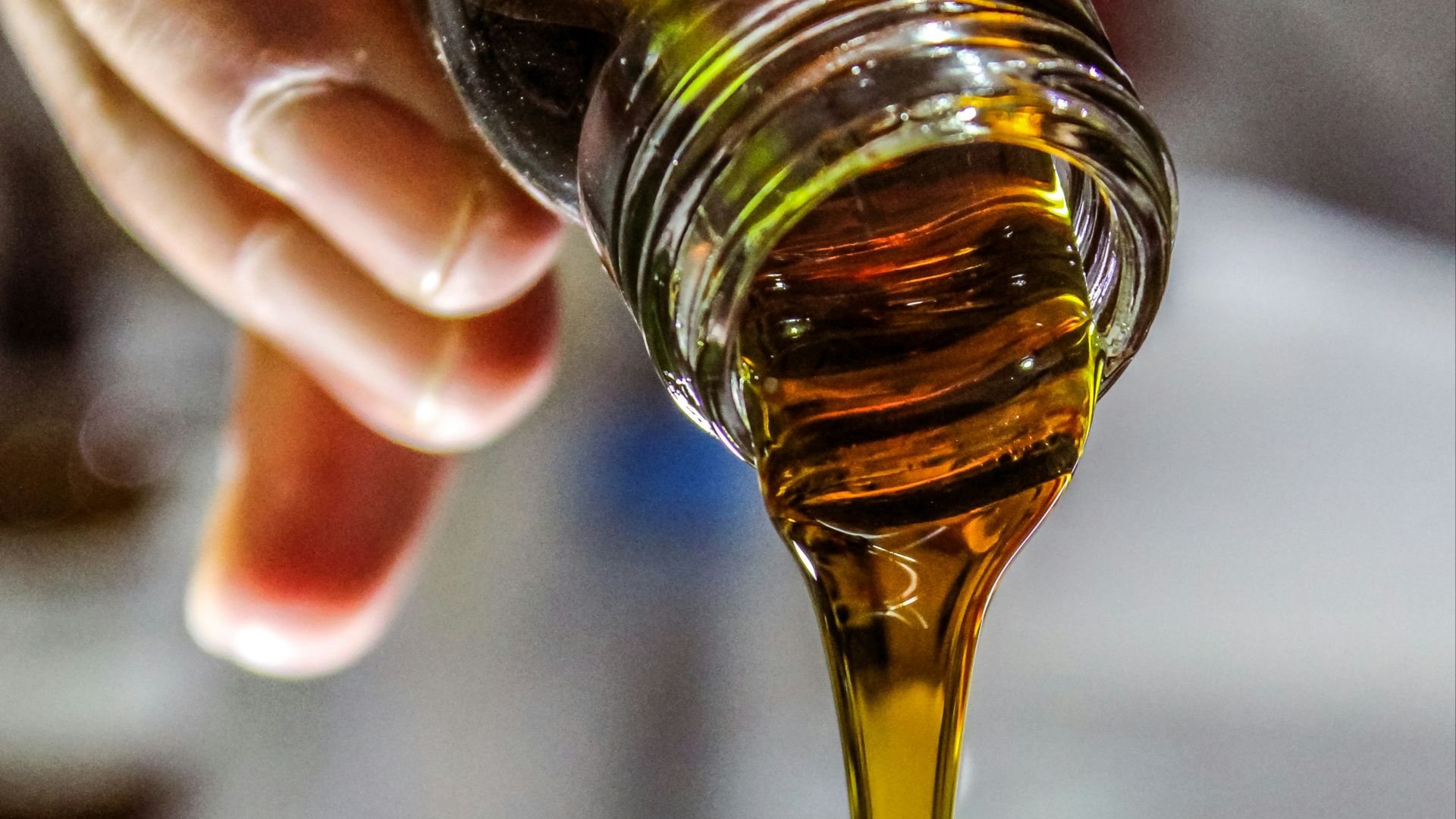 person holding clear drinking glass with brown liquid