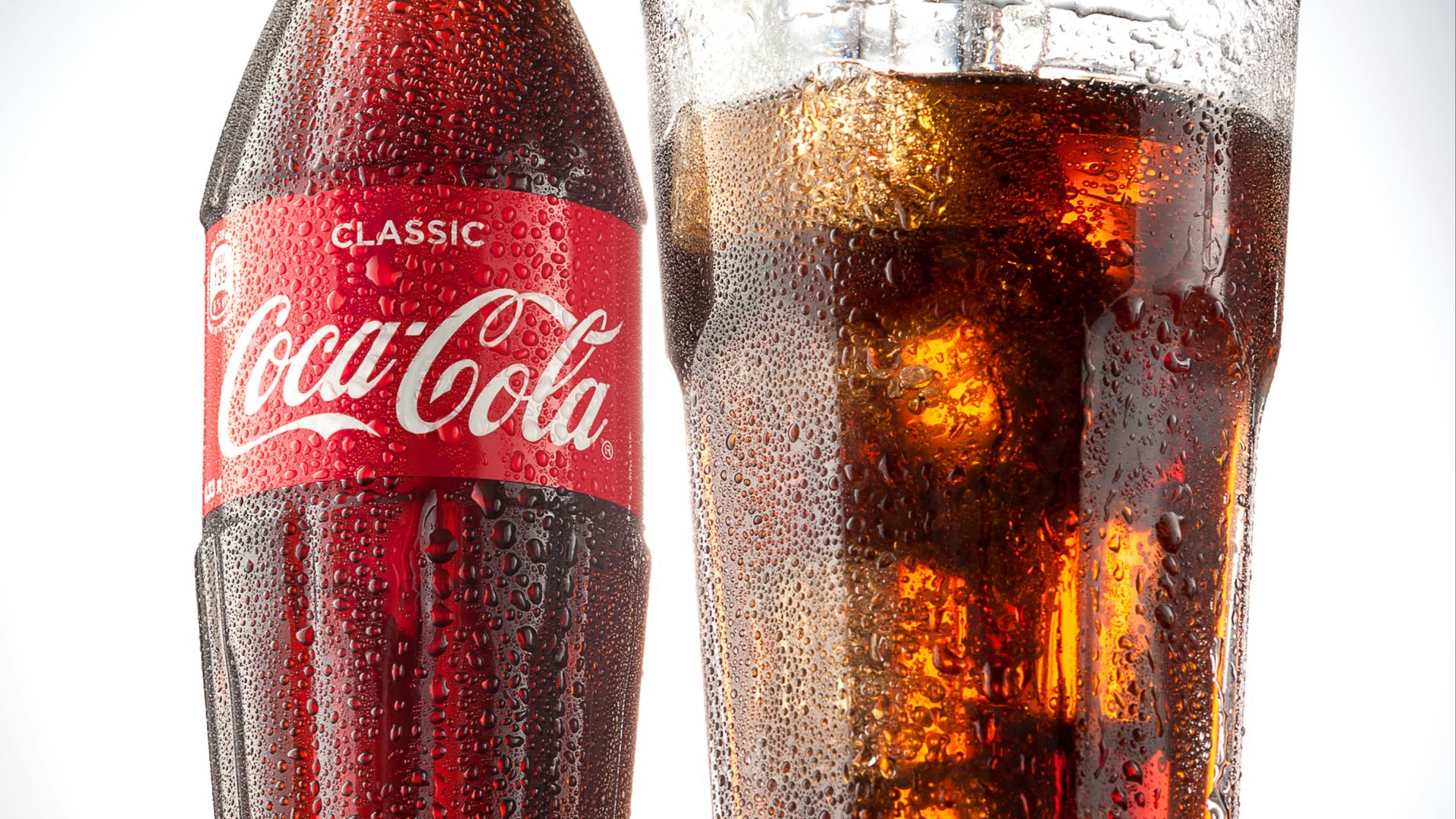 coca cola bottle beside drinking glass