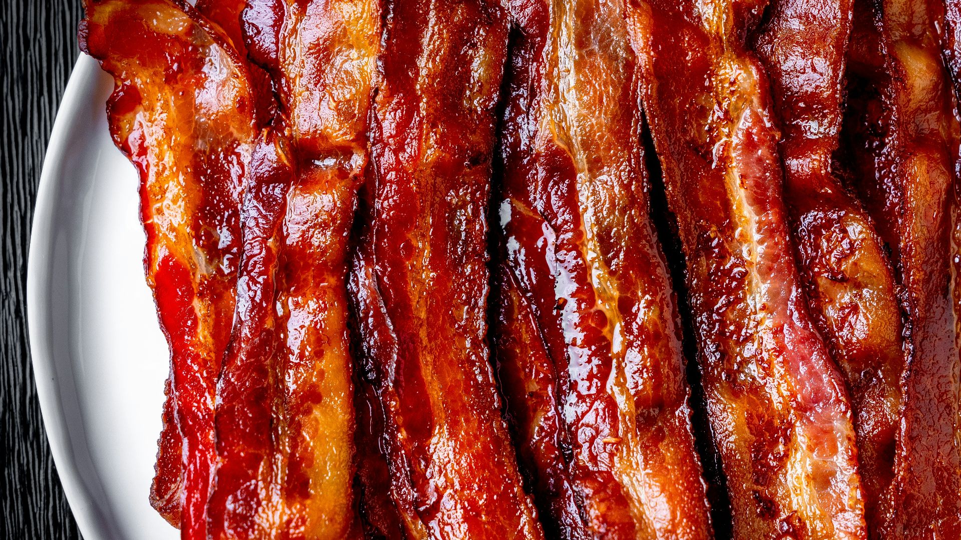 a white plate topped with bacon strips on top of a table