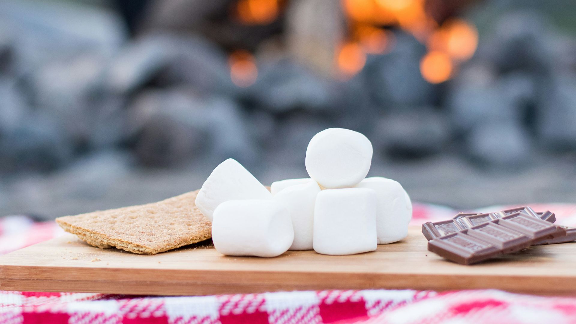 marshmallows and chocolate bar on brown wooden board