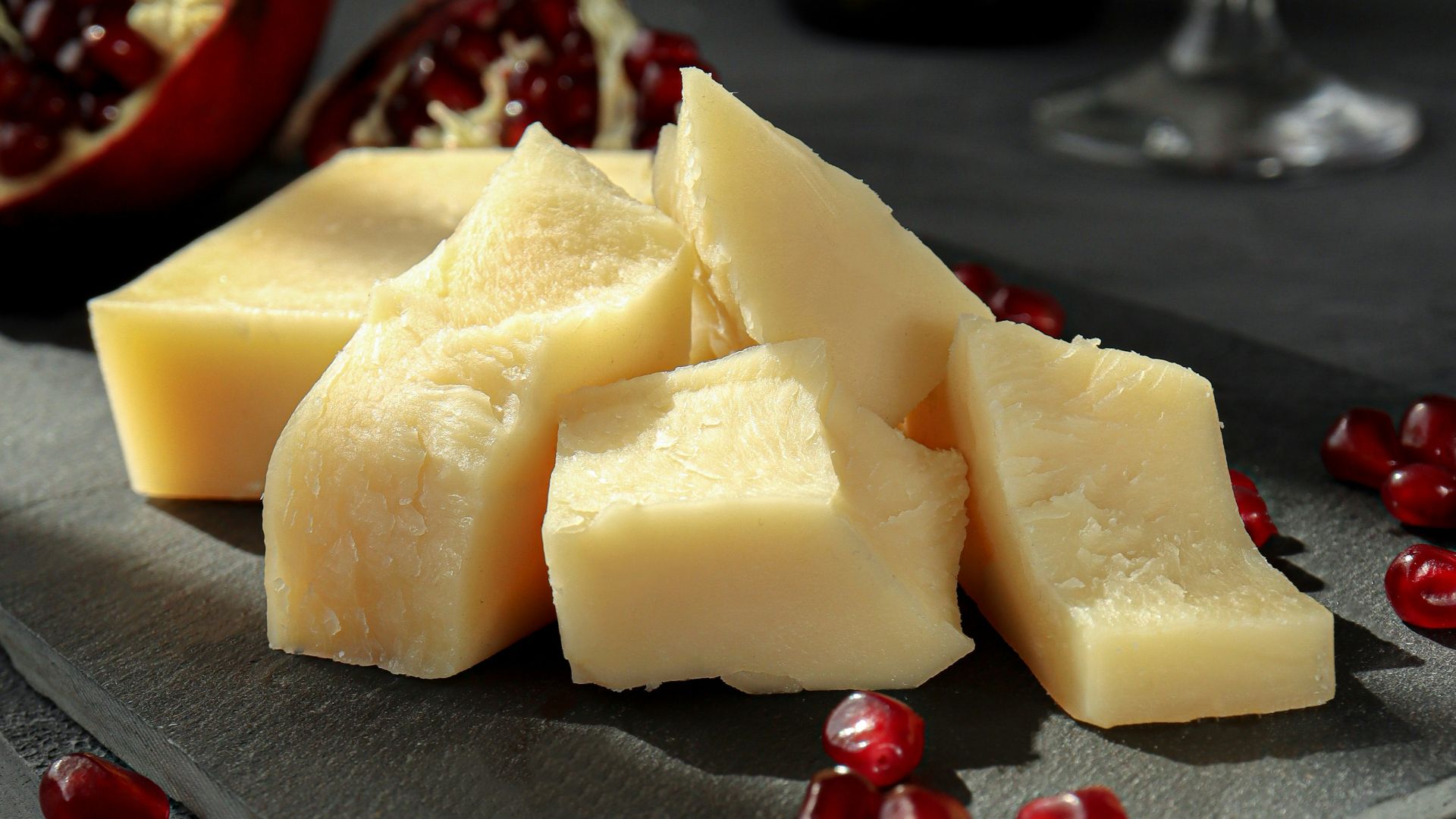 sliced cheese on black plate beside wine glass