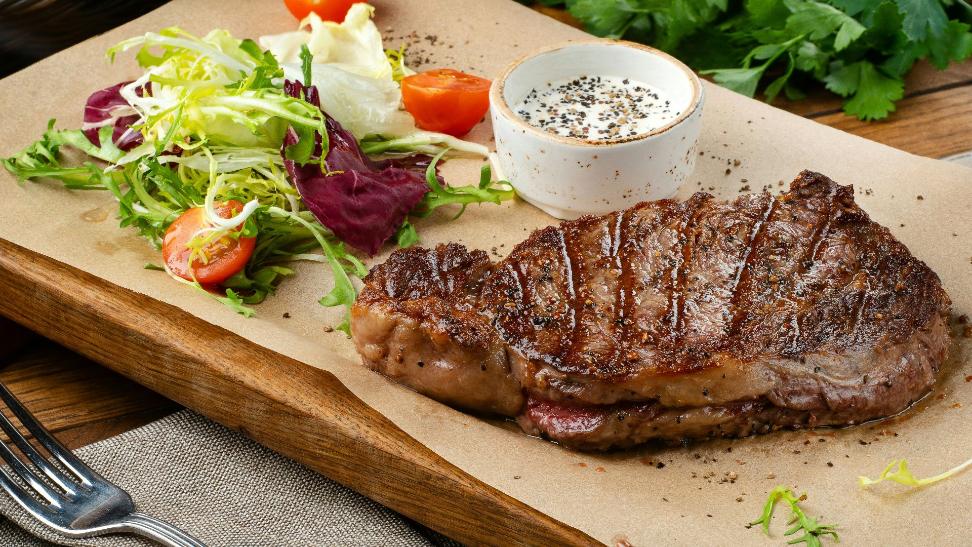 a steak with a side of salad and a glass of wine