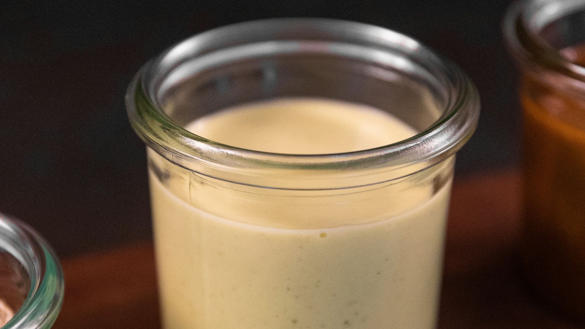 a wooden cutting board topped with jars filled with food
