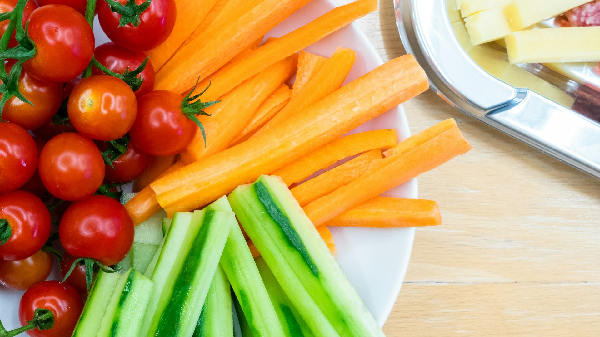 slices of carrots, zucchini, and cherry tomatoes on round white ceramic bowl