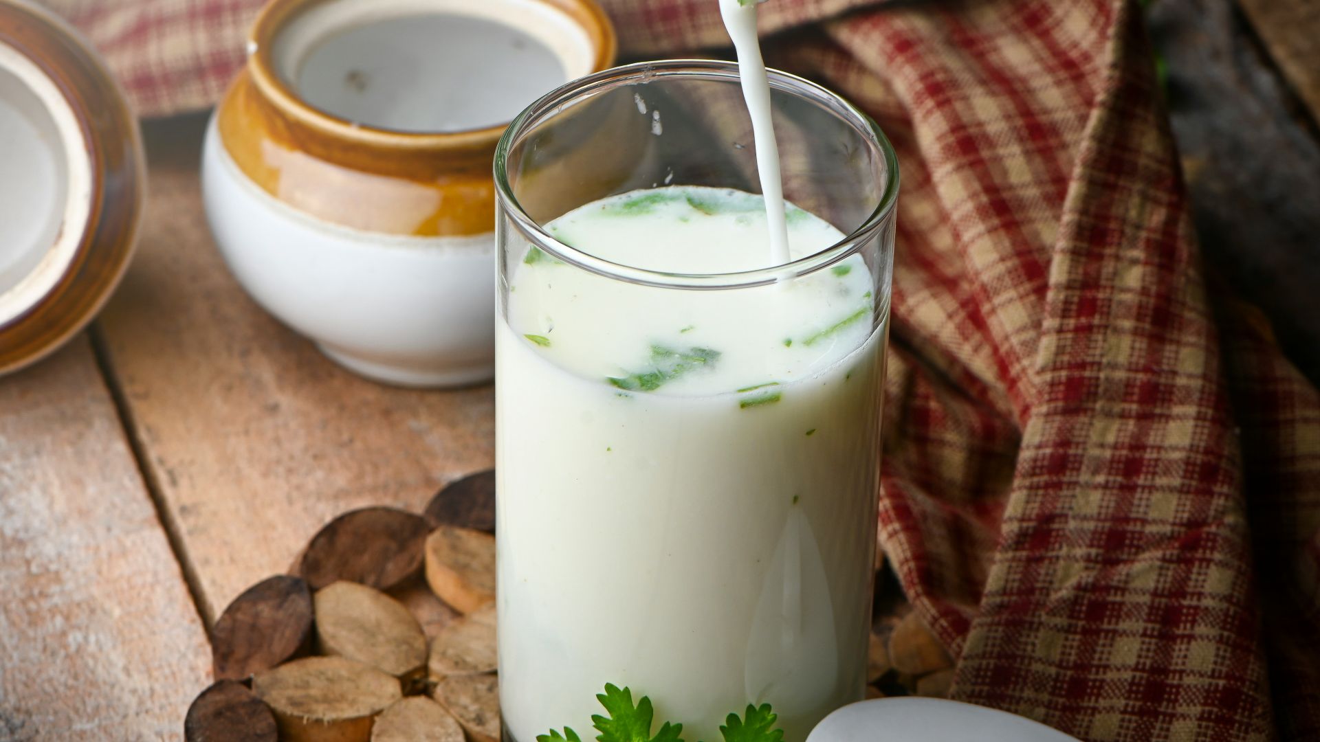 milk in clear drinking glass with green leaves and white cream