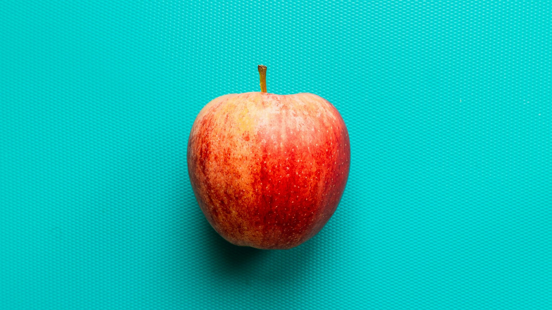 red apple fruit on blue surface