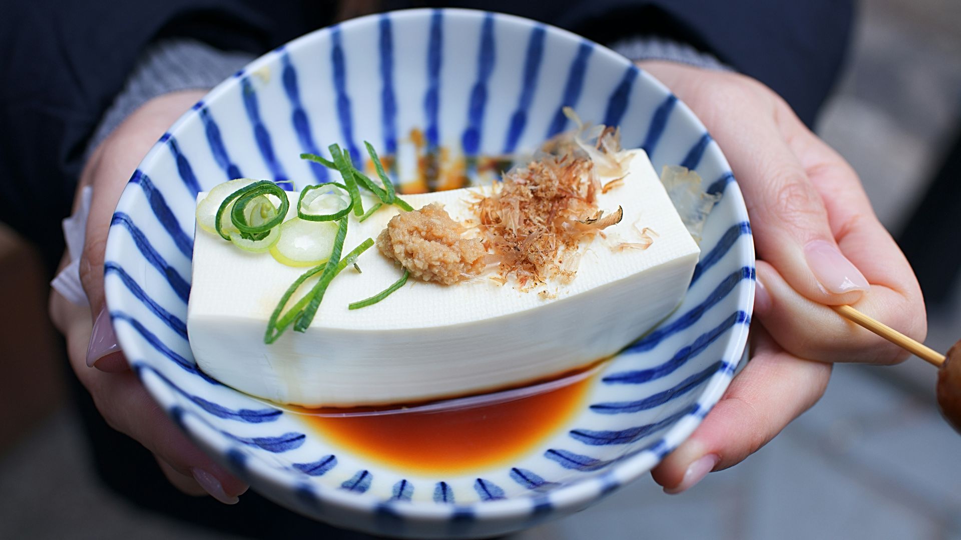 person holding white and blue ceramic plate with rice and sliced cucumber