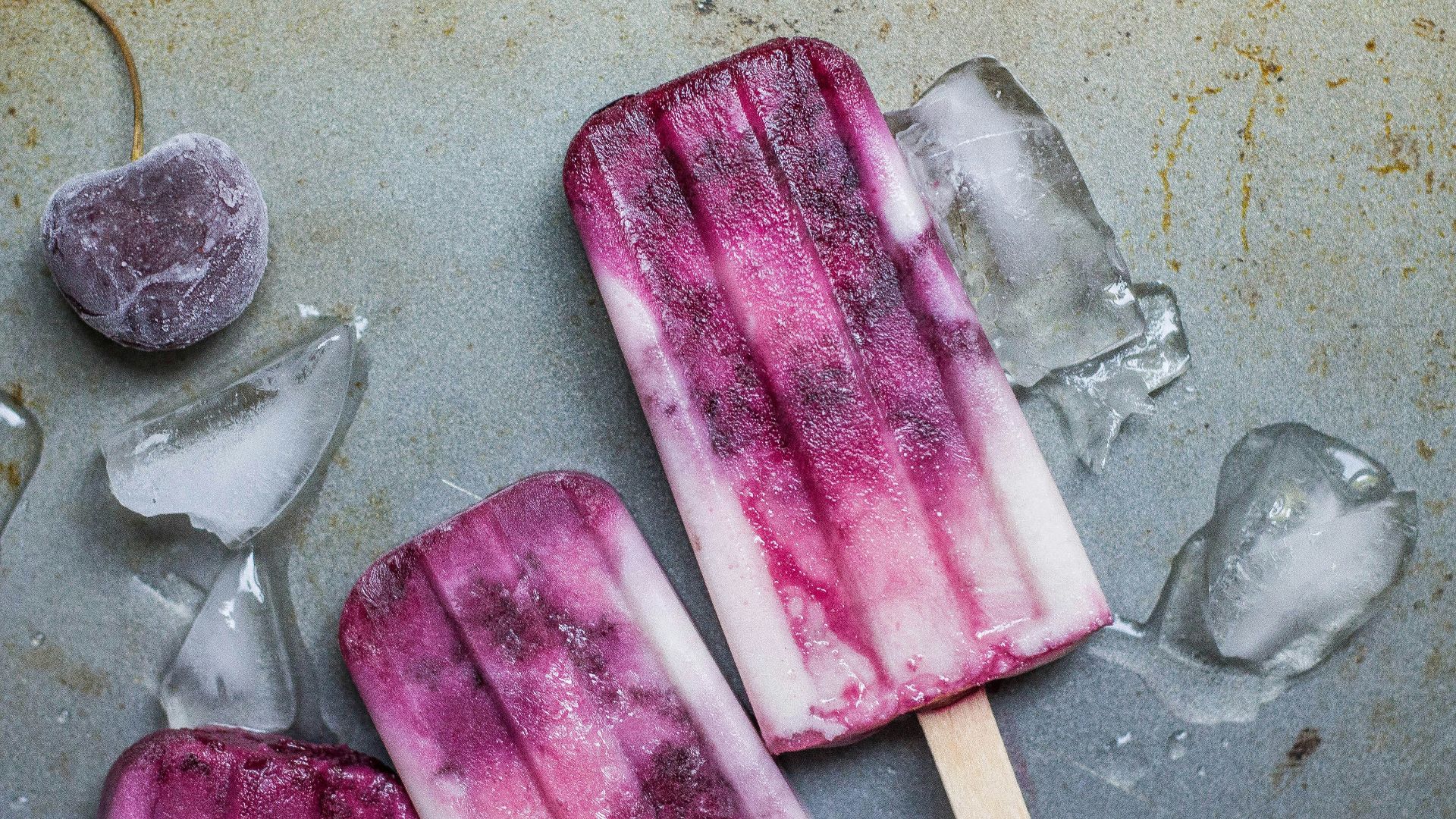 purple and white ice pop lying on wet ground with ice