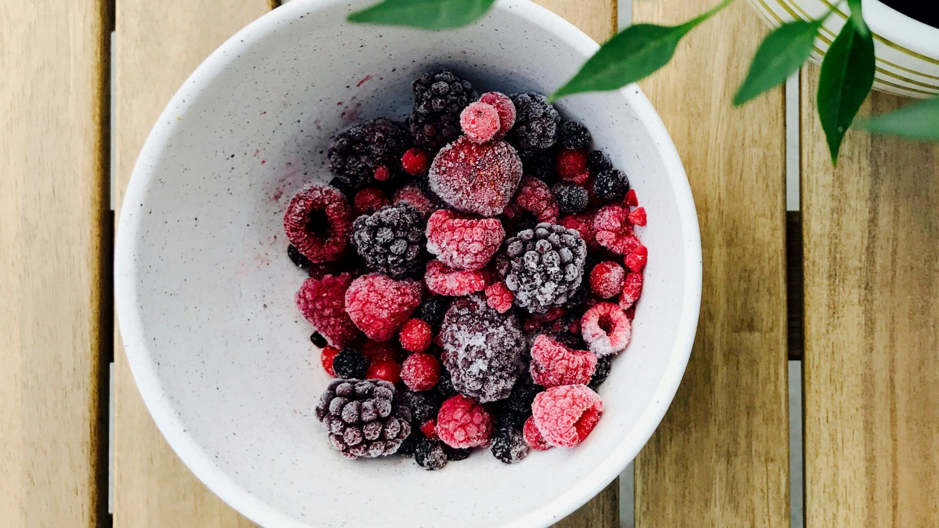 raspberries and black berries in white ceramic bowl